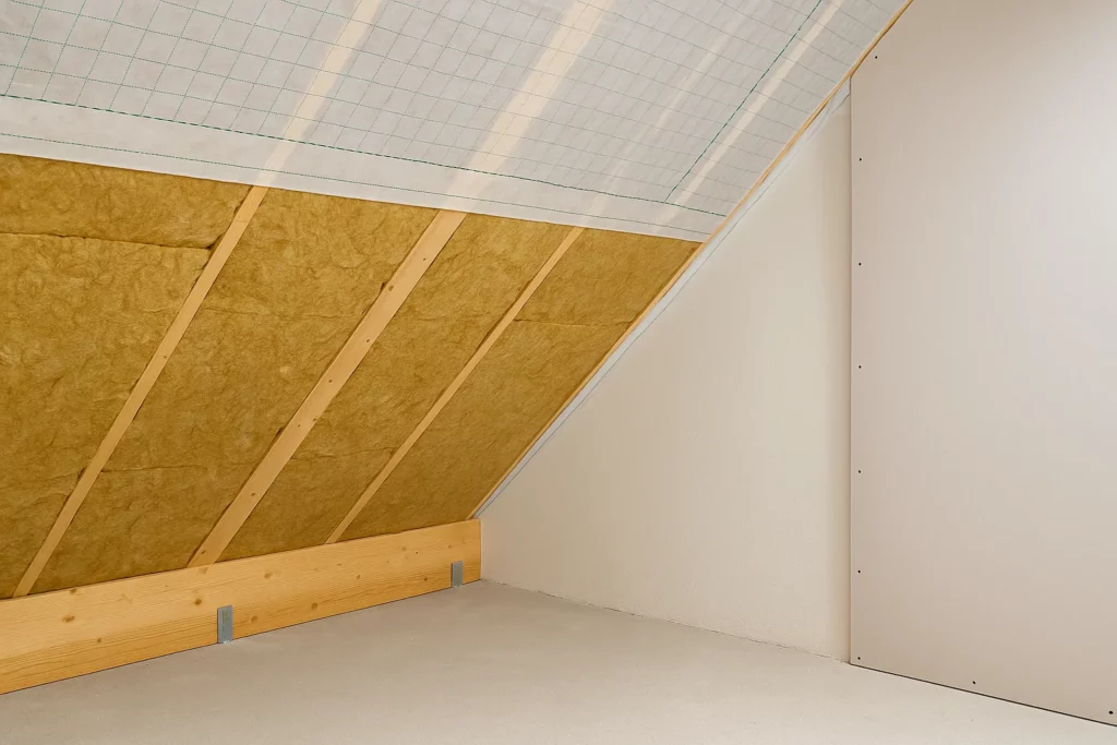 Isolation des rampants sous toiture avec laine minérale et structure en bois.