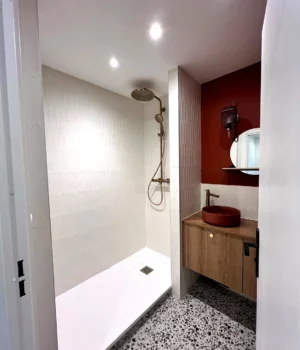 Salle de bain rénovée avec douche italienne, vasque terracotta et sol terrazzo