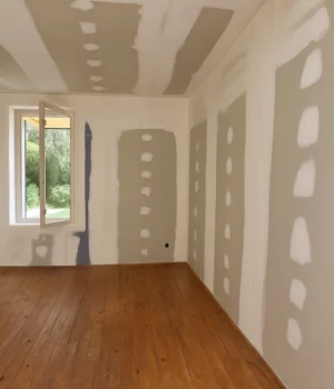 Travaux de plâtrerie avec bandes et enduits sur plaques de plâtre dans une chambre.